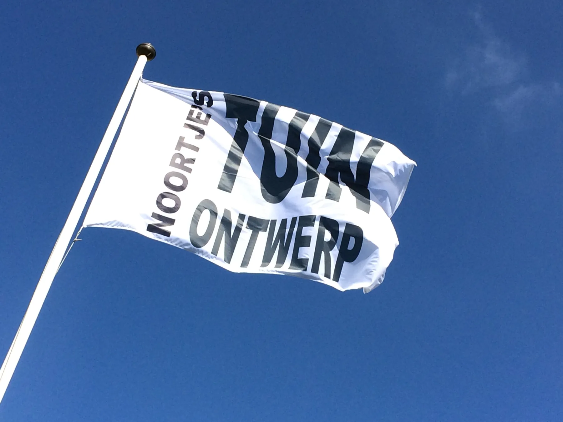 De vlag van Noortje’s TuinOntwerp tegen een blauwe lucht.